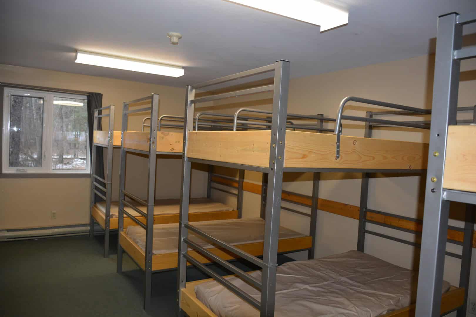 Bunk beds in a cozy indoor camping cabin at Camp Arnes, Manitoba. Perfect for family or group stays, offering comfortable sleeping arrangements surrounded by natural beauty.