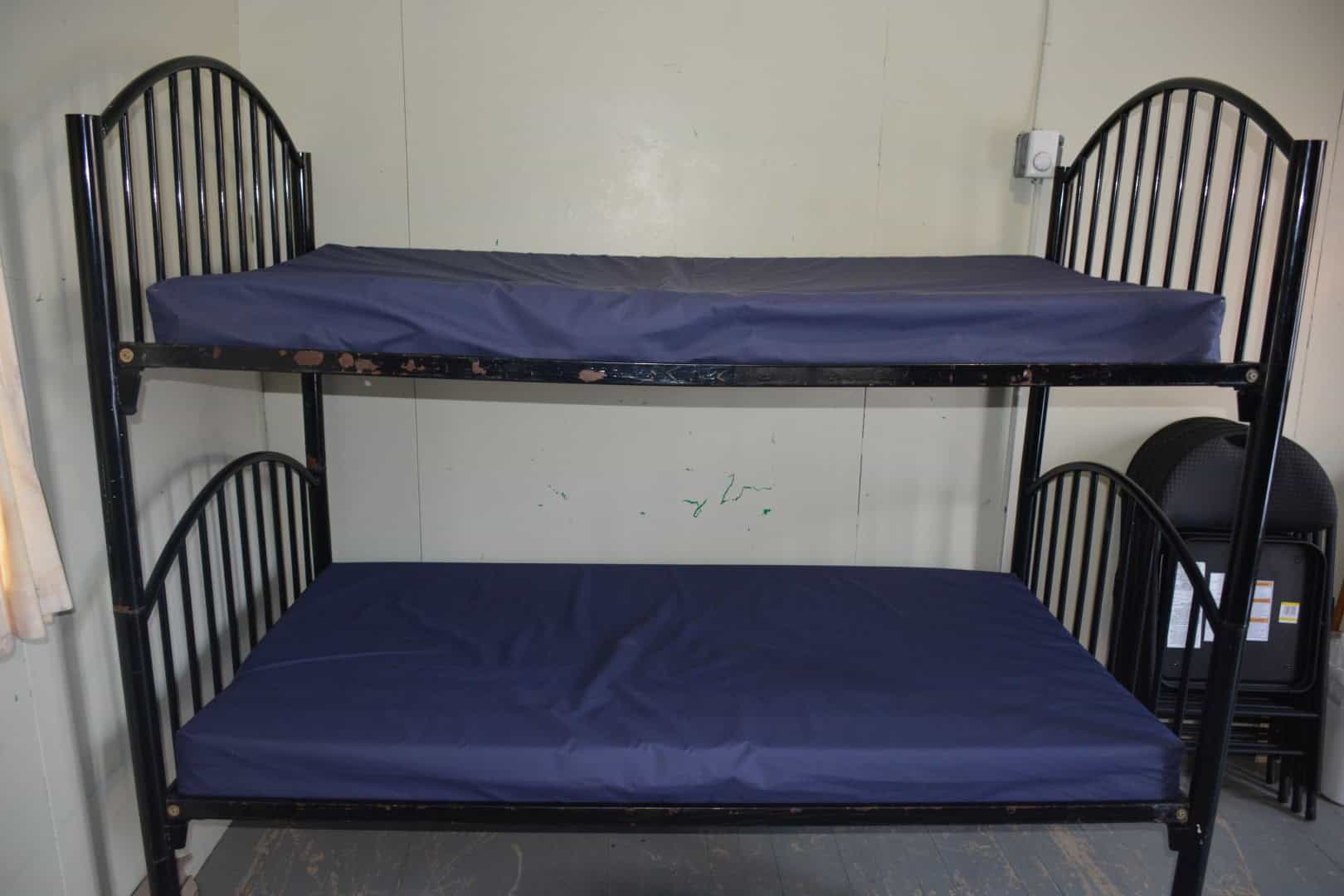 Bunk bed with blue mattresses and black metal frame at Camp Arnes, offering comfortable sleeping accommodations in a camp setting.