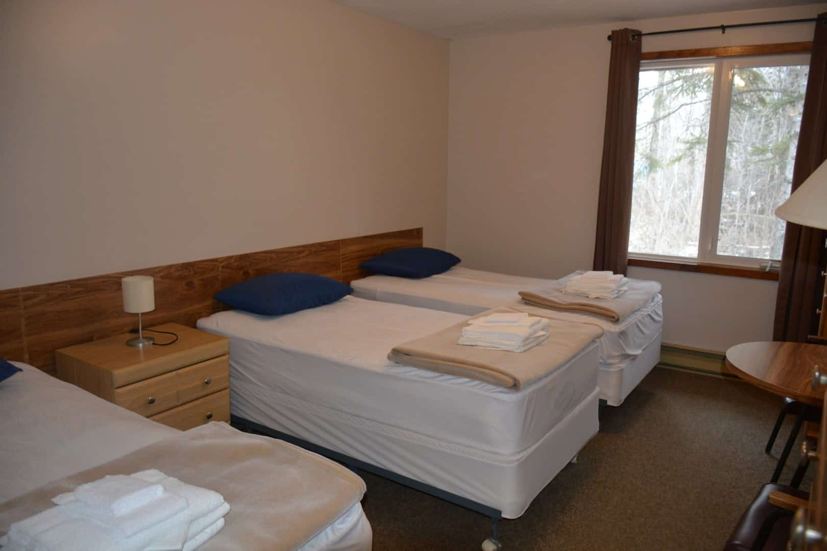 Comfortable guest bedroom at Camp Arnes with neatly made beds, cozy pillows, and fresh linens, ideal for relaxing stays in a scenic outdoor setting.