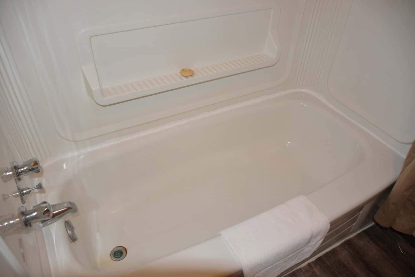 Modern white bathtub with chrome fixtures, inside a cozy bathroom at Camp Arnes. Perfect for relaxing after outdoor activities, featuring a towel draped over the edge for convenience.