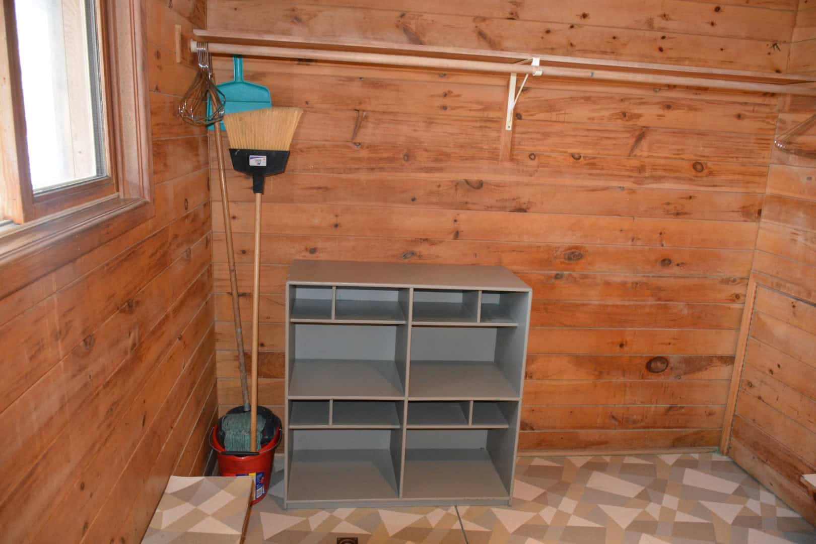 Spacious storage shed with wooden walls, cleaning supplies, broom, and shoe rack, ideal for camping gear organization at Camp Arnes.
