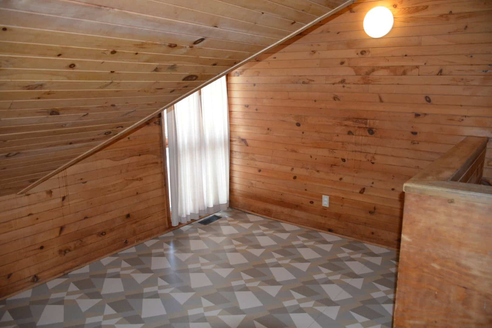 Bright wooden interior of a cozy cabin room at Camp Arnes featuring warm wood paneling and geometric patterned flooring. Perfect for relaxing stays and outdoor retreats in a natural setting.
