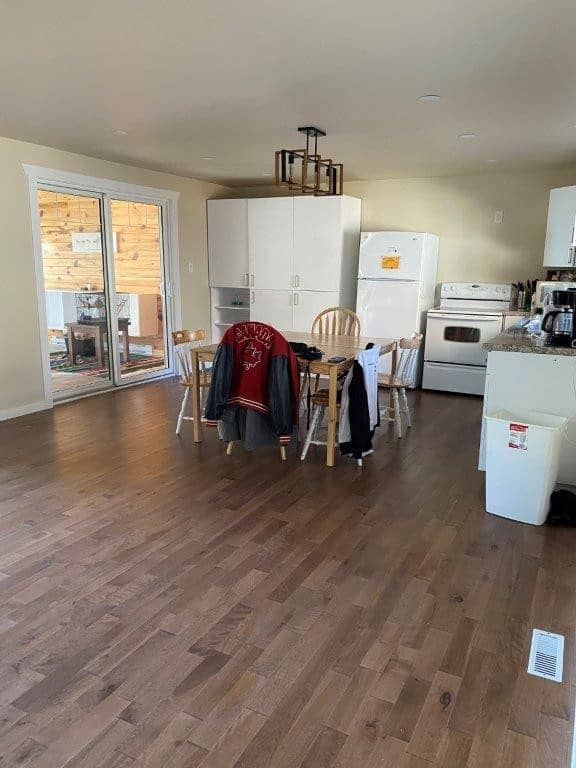 Spacious kitchen and dining area at Camp Arnes with wooden flooring, sliding glass door to outdoor patio, and modern appliances in a cozy lakeside retreat.