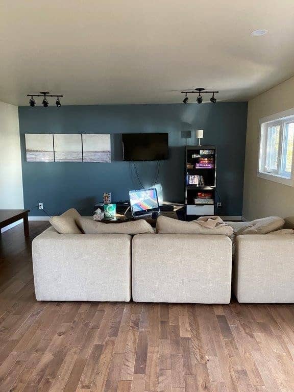 Cozy living room at Camp Arnes with comfortable sectional sofa, wall-mounted TV, and modern decor, perfect for relaxing and family gatherings during your stay.